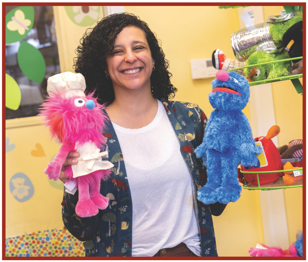 Nermeen Tahoun, owner of Boing! Toy Shop, smiling while holding two stuffed animals.