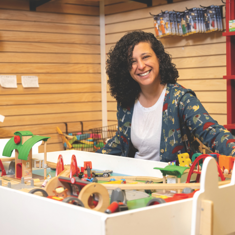 Boing! Toy Shop's owner Nermeen Tahoun sitting in front of the Jamaica Plain shop's play train station.
